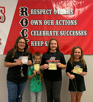 Four students in front of Red Rock banner holding award certificates