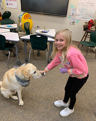 Little girl holding Darrien the Therapy Dog's paw.