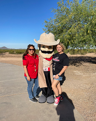 Two girls with a cowboy mascot with a large mustache