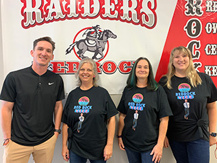 Staff members in front of Raiders sign