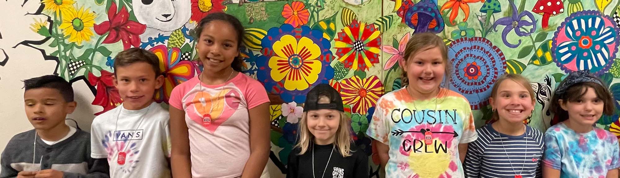 seven students standing in front of flower mural