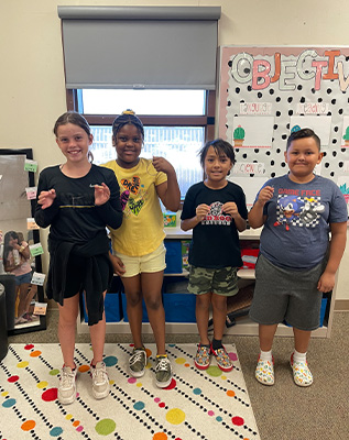 Students standing in front of a sign that reads Be Kind